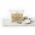 A  nylon pouch of Nan's Naturals Basic with Tallow goat milk soap  on a white marble board, with a small dish of white soap, a dropper, and lavender sprigs against a white background.